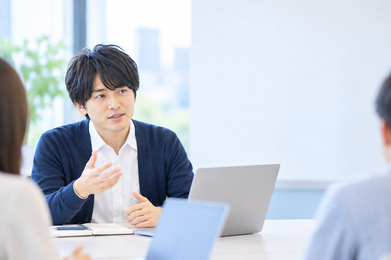 会議の場で、同僚に向かって落ち着いて話している会社員